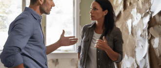 An insurance adjuster and homeowner having a tense discussion in a room with walls ripped open, showing water-stained insulation